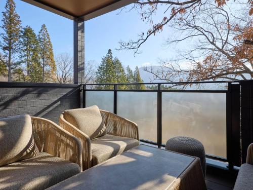 a balcony with two chairs and a table at Rakuten STAY VILLA Yufuin Onsen in Yufu