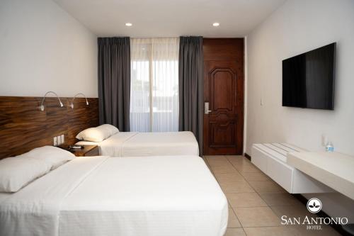 a hotel room with two beds and a flat screen tv at Hotel San Antonio in Tampico
