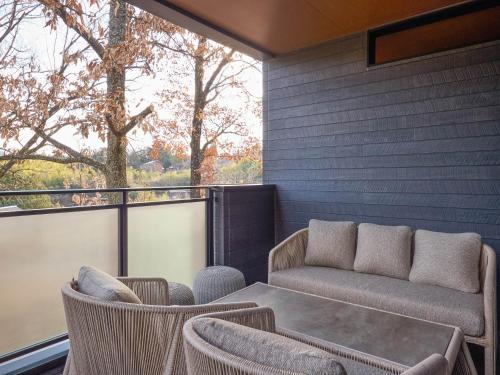 a patio with a couch and chairs on a balcony at Rakuten STAY VILLA Yufuin Onsen in Yufu