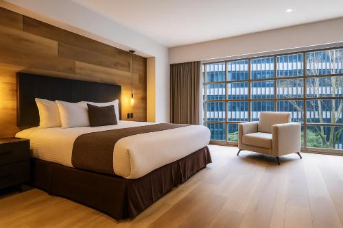 a bedroom with a large bed and a chair at St Isidro Suites Corporate Housing SPA & Wellness Center in Mexico City