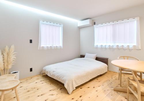 a white bedroom with a bed and a table at Cortile in Mitoyo