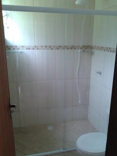 a bathroom with a glass shower with a toilet at Maresias Flats Unidade I in Maresias