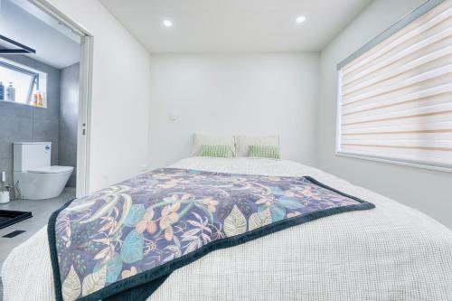 a bedroom with a bed with a colorful blanket on it at Boutique Hillside Heaven near AKLD Airport in Auckland
