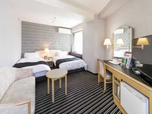 a hotel room with two beds and a desk at APA Hotel Fujichuo in Fuji