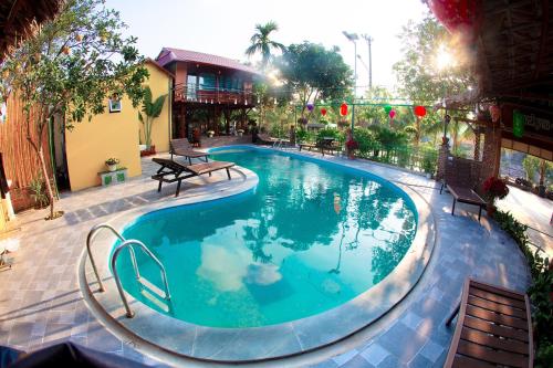 a large swimming pool in a yard with benches around it at Tam Coc Riverside Bungalow in Ninh Binh