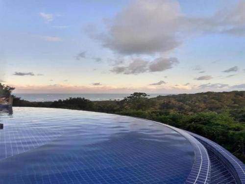a swimming pool with a view of the ocean at Flat Villas do Pratagy: Tranquilidade e Natureza ao Norte de Maceió in Maceió
