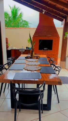 a long wooden table with chairs and a brick fireplace at Pousada luz do Sol in Cacoal