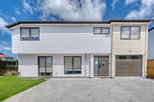 a white house with a garage at Elegant & Peaceful in Auckland Vicinity in Auckland
