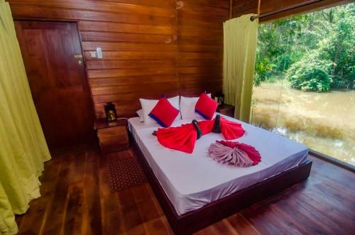 a bedroom with a bed with red pillows and a window at Harmony by the lake in Dambulla