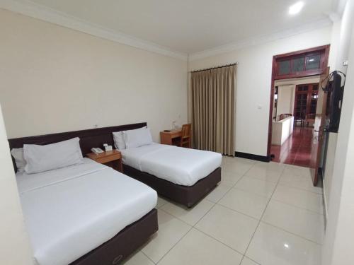 a hotel room with two beds and a balcony at Aurora Hotel Kartini in Cirebon