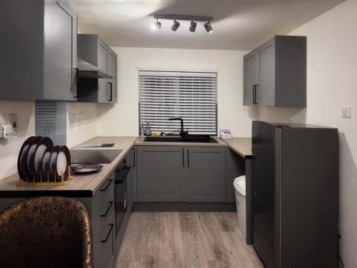 a kitchen with gray cabinets and a black refrigerator at Valley house in Nottingham
