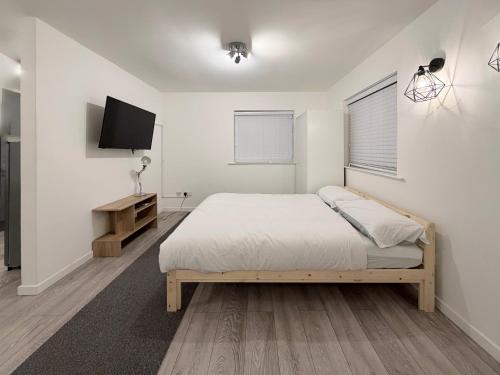 a white bedroom with a bed and a tv at Valley house in Nottingham