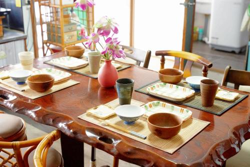 a wooden table with plates and bowls on it at ラベンダー畑まで5分ー最大10人ーお餅つきー流しそうめんー花火ー五右衛門風呂ー心と身体が元気になる古民家民泊ーオモテナシロッジ悠遊 in Nakafurano