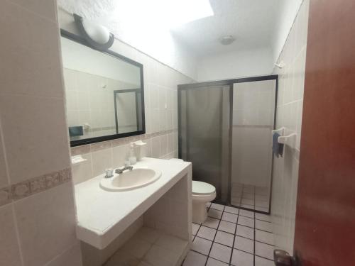 a bathroom with a sink and a toilet and a mirror at Casa Luna in Barra de Navidad