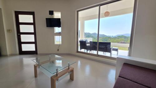 a living room with a glass table and a large window at Casa Chaue in Tangolunda