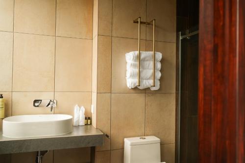 a bathroom with a sink and a toilet and towels at Casa Don Cristóbal Hotel y Restaurante Boutique in San Juan La Laguna