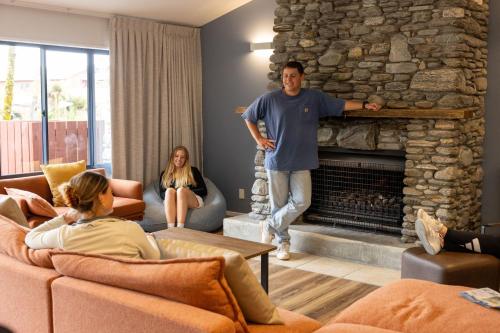 a man standing in a living room with a fireplace at Haka House Franz Josef in Franz Josef
