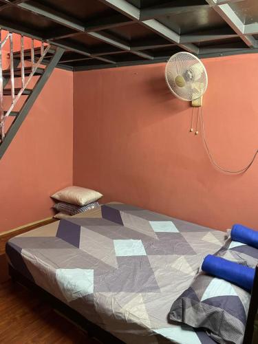 a bedroom with a bed with a fan and a staircase at VJ Homestay in Jasin