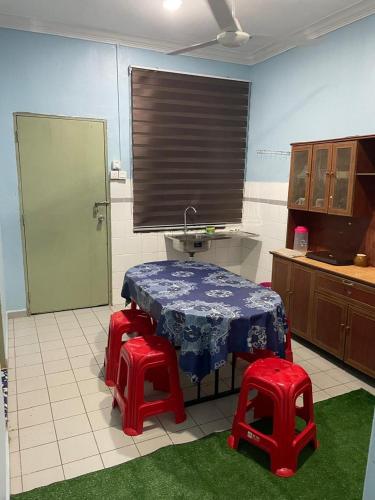 a kitchen with a table and two red stools at VJ Homestay in Jasin