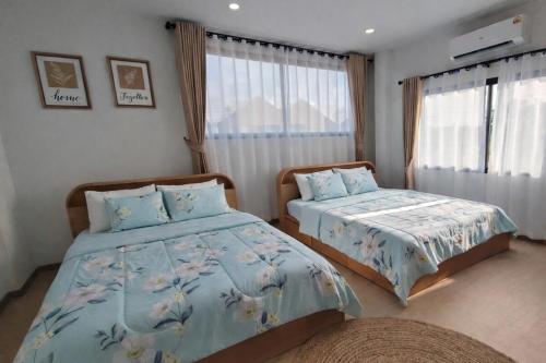 a bedroom with two beds and two windows at Dolce Home suratthani in Suratthani