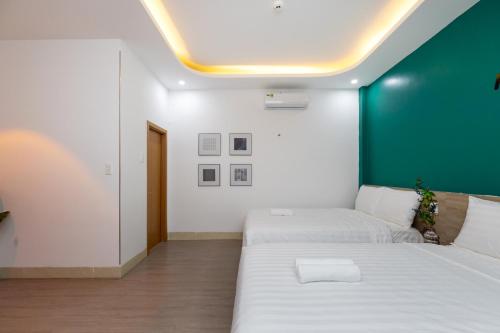 a bedroom with two beds and a green wall at E Stay Boutique in Vung Tau