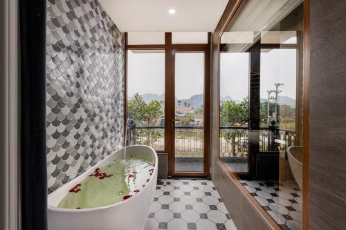 a bathroom with a tub and a large window at Pataco Tam Coc Hotel in Vũ Lâm