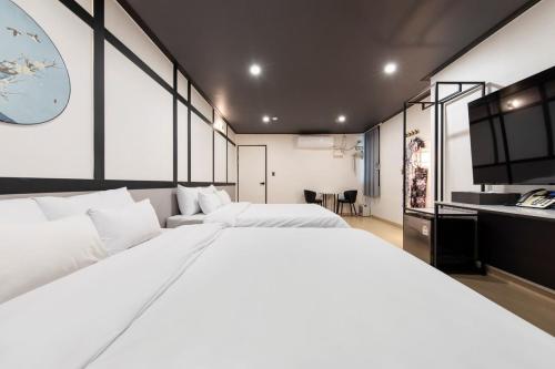 a large white bed in a room with a kitchen at Ryokan Stay in Gangneung