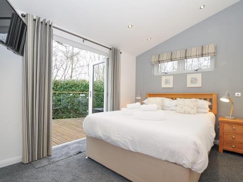 a bedroom with a large white bed and a sliding glass door at 15 Faraway Fields in Liskeard