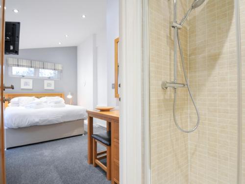 a bedroom with a shower and a bed and a desk at 15 Faraway Fields in Liskeard