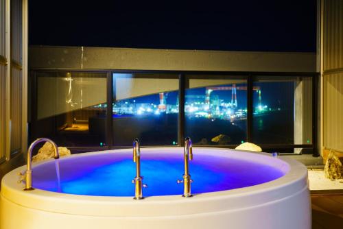 a bath tub with two faucets in front of a window at Business Resort Kyuan in Oita
