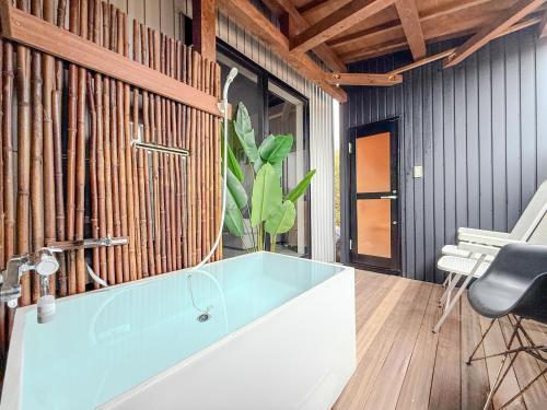 a bathroom with a tub and a chair and a plant at 海宿ニシノヤ in Shioya