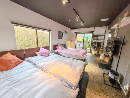 two large beds in a room with a large window at 海宿ニシノヤ in Shioya