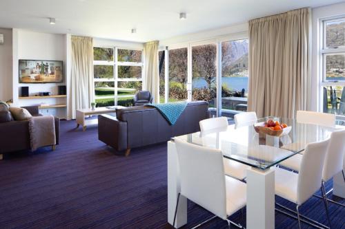 a living room with a glass table and white chairs at Marina Apartments - Element Escapes in Queenstown