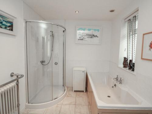 a white bathroom with a shower and a tub at Full Deck in Dartmouth
