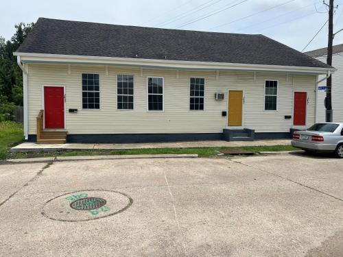 a white house with red doors and a car parked in front at Trisuites 2 in New Orleans