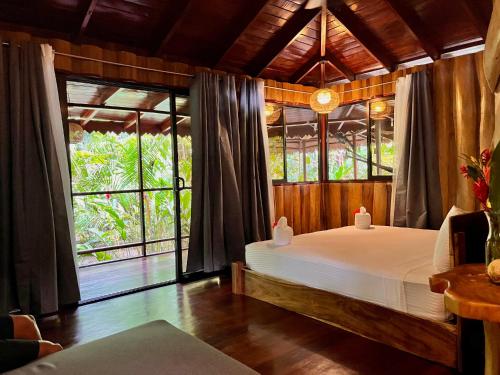 a bedroom with a bed and a large window at Hotel La Costa de Papito in Puerto Viejo