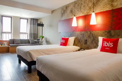 two beds with red pillows in a hotel room at Ibis Dujiangyan in Dujiangyan