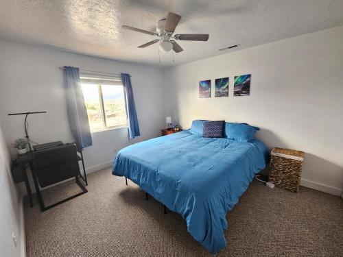 a bedroom with a blue bed and a ceiling fan at Mountain View near Zion in Hurricane