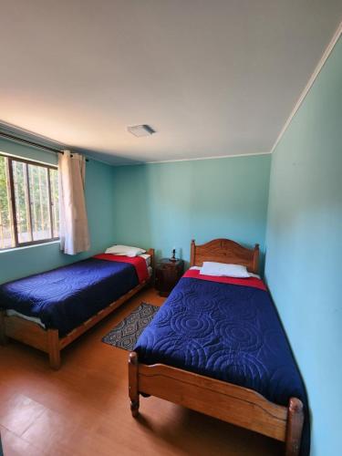 two beds in a room with blue walls at Algarrobo, house in a condominium in Algarrobo