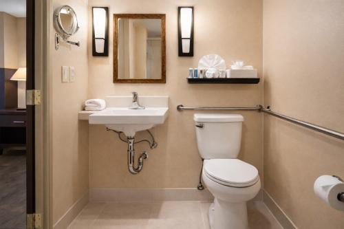 a bathroom with a toilet and a sink at The Buena Park Grand Hotel & Suites in Buena Park