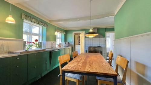 a kitchen with green walls and a wooden table and chairs at Historic Farmhouse From 1848 in Hårby