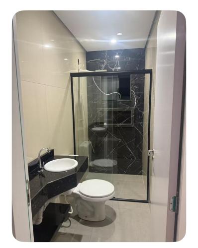 a bathroom with a toilet and a glass shower at Apartamento Casa pontarolo in Guarapuava