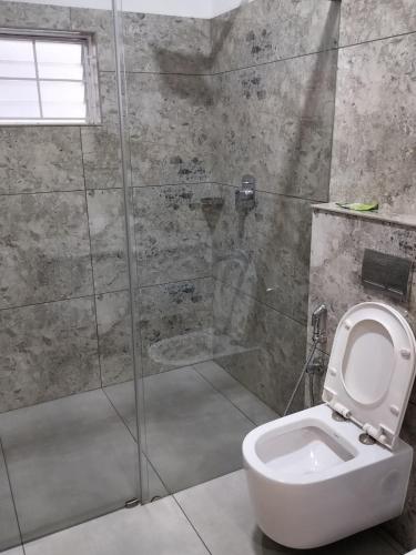 a bathroom with a toilet and a glass shower at Caesars fitness in Jāmb