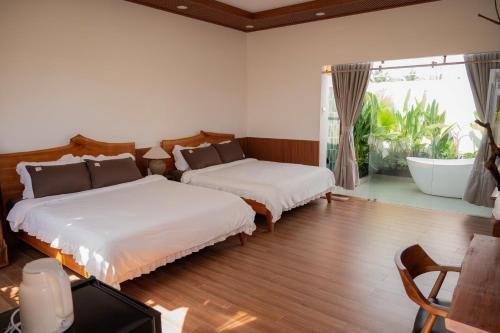 a bedroom with two beds and a large window at MAISON à SADEC in Ấp Tân An (2)