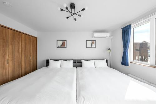 a bedroom with a white bed and a window at Hills Niseko C in Niseko