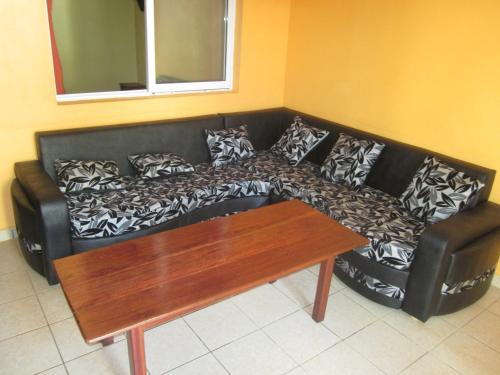 a black couch in a living room with a wooden table at Residence Kathyly in Diego Suarez