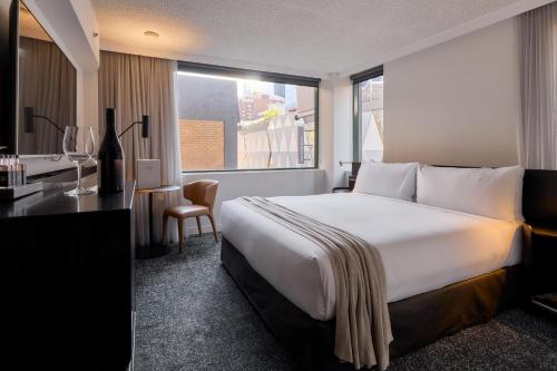 a hotel room with a large bed and a desk at Lancemore Crossley St. Melbourne in Melbourne