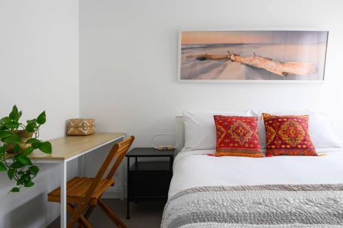 a bedroom with a bed and a desk next to a bed sidx sidx at 42 Coogee Beach Marina 3BR Haven near Omeo Wreck in Coogee