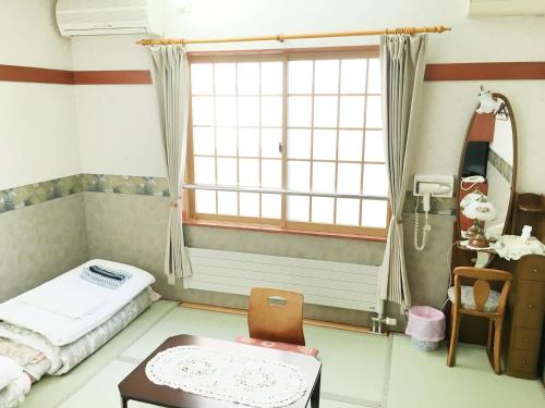 Zimmer mit einem Bett, einem Fenster und einem Tisch in der Unterkunft Pension Puppy Tail in Hakodate