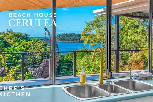 a kitchen with a sink and a window with a bird cage at Absolute Beachfront with Ocean Views 3 Beds plus Pool in Hideaway Bay